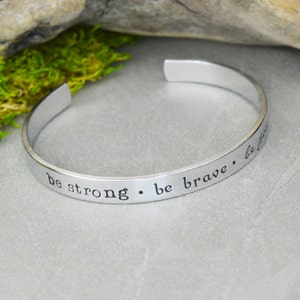 Pode incluir: Pulseira de bracelete de prata com a inscrição "be strong. be brave. be you".