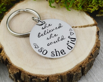 Brelok z ręcznie stemplowanym napisem: „She Believed She Could”