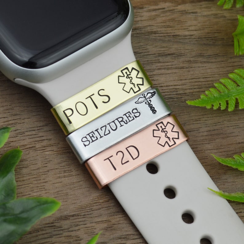 K&ouml;nnte beinhalten: Drei Metall-Armb&auml;nder f&uuml;r Uhren mit medizinischen Warnsymbolen und Text. Die B&auml;nder sind in Gold, Silber und Ros&eacute;gold gehalten. Der Text auf den B&auml;ndern lautet "POTS", "SEIZURES" und "T2D".
