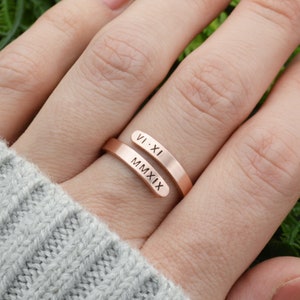 May include: A rose gold ring with two bands, one engraved with "VI-XI" and the other with "MMXIX".