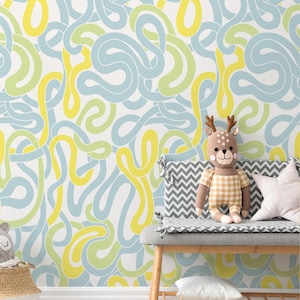 May include: A light blue and yellow abstract pattern wallpaper with a grey and white chevron patterned bench with a stuffed deer toy sitting on it.
