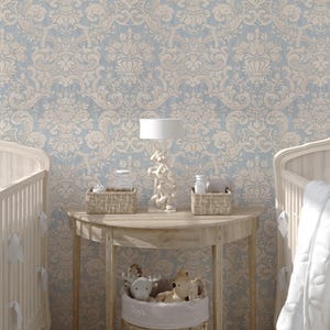May include: A semi-circular wooden console table sits between two cribs against a blue and cream damask wallpaper. On the table are two woven baskets, a white lamp, and a woven basket on the floor labeled Toys with plush animals.