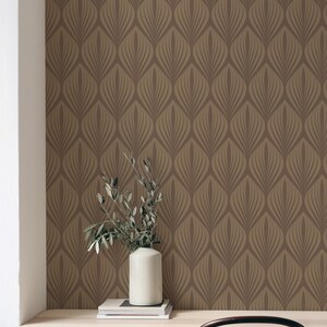 May include: A brown and gold geometric patterned wallpaper with a white vase and green plant branches on a wooden desk with a black chair.