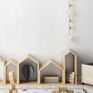 May include: A white wall with a textured pattern, a wooden shelf unit with a black globe and wooden blocks that spell "AMZ" and "CS", and a white rug with black stars.