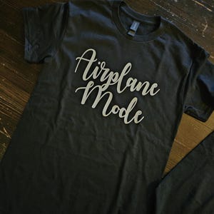 May include: A black t-shirt with the text "Airplane Mode" printed in white on the front.