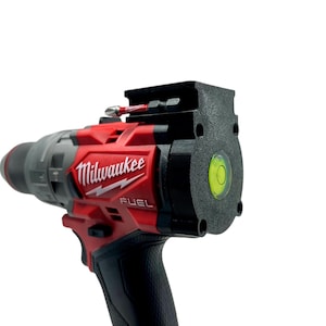 May include: A red and black Milwaukee FUEL drill with a level attached to the top. The level is green and has a bubble in the center.