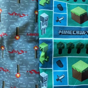 Puede incluir: Dos paneles de tela con tem&aacute;tica de Minecraft. Un panel es gris con antorchas rojas y la palabra "CRAFT". El otro panel es verde, azul y marr&oacute;n con im&aacute;genes de un creeper, un esqueleto, una espada, un bloque de tierra y la palabra "MINECRAFT".