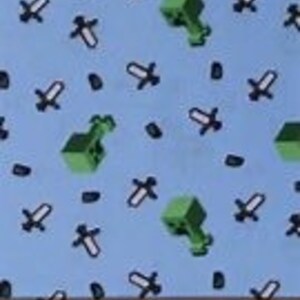 Puede incluir: Tela azul con un patr&oacute;n repetido de bloques de Minecraft verdes, espadas y diamantes negros.