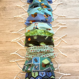 Puede incluir: Un conjunto de 10 mascarillas faciales con varios dise&ntilde;os de Minecraft. Las mascarillas est&aacute;n hechas de tela y tienen lazos el&aacute;sticos blancos para las orejas. Los dise&ntilde;os incluyen un patr&oacute;n pixelado verde y negro, un patr&oacute;n azul y verde con un personaje de Minecraft y un patr&oacute;n rojo y blanco con corazones y espadas.