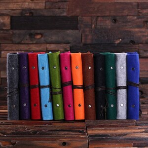 May include: A set of 14 rolled-up felt journals in various colors, including gray, purple, red, blue, green, pink, orange, brown, black, dark green, light gray, and blue. Each journal has a leather strap and a tassel.