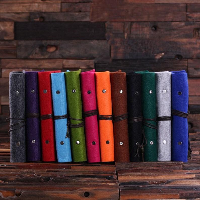 May include: A set of 14 rolled-up felt journals in various colors, including gray, purple, red, blue, green, pink, orange, brown, black, dark green, light gray, and blue. Each journal has a leather strap and a tassel.