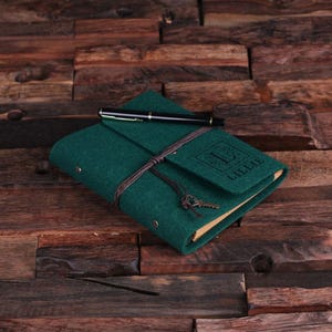 May include: A green felt journal with a brown leather strap and a key charm. The journal has a personalized name, "Lillie", embossed on the front cover.