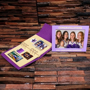 May include: Purple scrapbook with photos of cheerleaders and the text "Cheer Squad" and "2020 Cheerleading Champions".