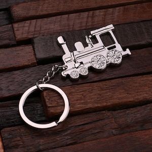 May include: Silver-toned train keychain with a detailed design and a silver key ring.