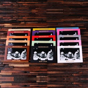 May include: A set of 10 picture frames in various colors, each with the word "BRIDESMAID" and the date "MAY 1928" printed on the front. The frames are arranged in a row, with the colors alternating.