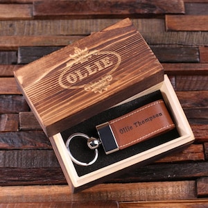 May include: A brown leather keyring with the name "Ollie Thompson" engraved on it. The keyring is in a wooden box with the name "Ollie" engraved on the lid.