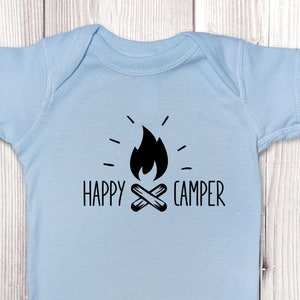 Op de afbeelding: Lichtblauwe baby romper met een zwarte afbeelding van een kampvuur en de tekst "HAPPY CAMPER".
