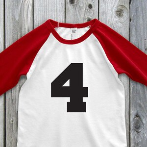May include: A white and red raglan-style shirt with the number 4 in black on the front. The sleeves are red, and the body is white. The shirt is made of a soft material.