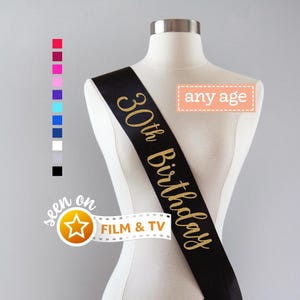 May include: A black satin sash worn across a mannequin torso, featuring the gold glitter text 30th Birthday. A column of small colored squares is displayed to the left, with a rectangular box labeled any age and a film strip graphic with a star.