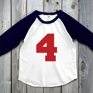 May include: White and navy blue baseball style shirt with the number 4 in red on the front. The shirt has navy blue sleeves and a white body. The number 4 is large and centered on the front of the shirt.