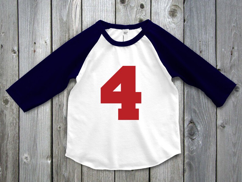 May include: White and navy blue baseball style shirt with the number 4 in red on the front. The shirt has navy blue sleeves and a white body. The number 4 is large and centered on the front of the shirt.