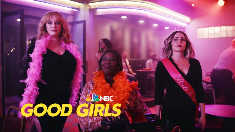 May include: Three women in a dimly lit bar, wearing party attire. The woman in the center is wearing an orange feather boa and a brown patterned dress. The woman on the left is wearing a pink feather boa and a black dress. The woman on the right is wearing a black dress with a pink sash that says "Bride to be" and a tiara. The text "GOOD GIRLS" is in yellow letters on a black background in the foreground of the image. The NBC logo is in the lower left corner of the image.