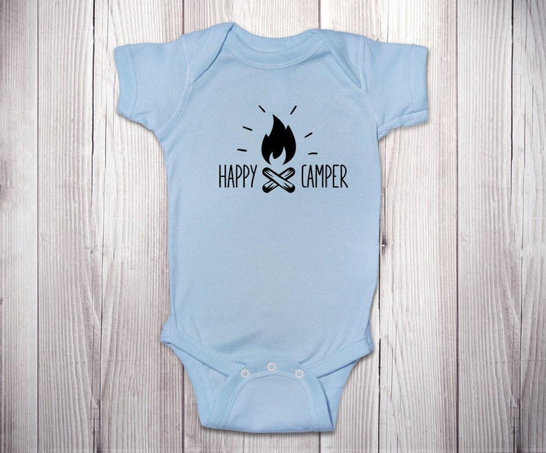 Op de afbeelding: Lichtblauwe baby romper met een zwarte afbeelding van een kampvuur en de tekst "HAPPY CAMPER".