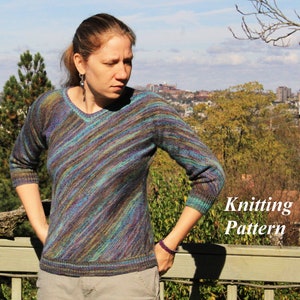 Puede incluir: Un suéter de punto con cuello en V y mangas largas. El suéter presenta rayas diagonales en tonos de azul, verde, morado y marrón. El texto "Knitting Pattern" es visible en el lado derecho de la imagen. La persona lleva pantalones grises.