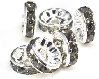 May include: Five silver-toned spacer beads with a row of black rhinestones around the edge. The beads have a hole in the center for stringing.
