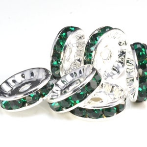 May include: Silver-toned bead spacers with a single row of emerald green rhinestones around the edge.