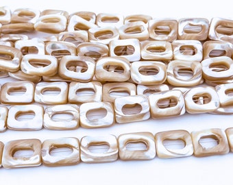 Op de afbeelding: Een streng beige vierkante schelp kralen met een gat in het midden van elke kraal. De kralen hebben een parelmoer afwerking.