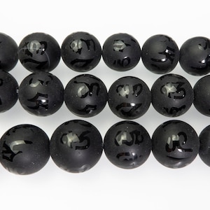 May include: A strand of black beads with engraved symbols. The beads are matte and have a slightly rough texture.