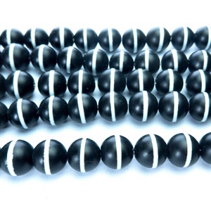May include: A strand of black and white agate beads. The beads are round and have a smooth, polished finish.