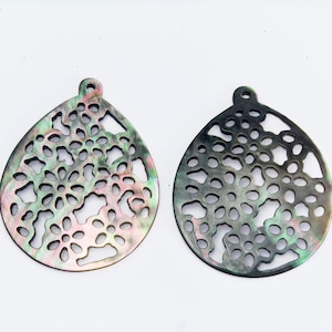 May include: Two black and iridescent shell pendants with a delicate floral cutout design.