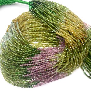 May include: A strand of green, pink, and yellow gemstone beads. The beads are faceted and have a round shape. The strand is approximately 40 cm long.