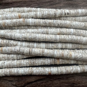 May include: A strand of white and gray round beads made from natural stone. The beads are stacked on top of each other, creating a textured pattern.