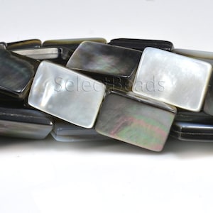 以下が含まれることがあります： 黒と白の長方形の貝殻ビーズのストランド。ビーズは滑らかで磨かれた仕上げで、わずかに虹色の光沢があります。