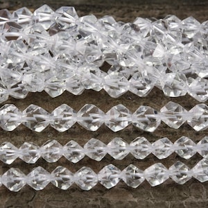 Puede incluir: Una hebra de cuentas de cristal facetadas transparentes. Las cuentas están dispuestas en filas y todas son del mismo tamaño y forma. Las cuentas están hechas de cuarzo transparente y tienen un acabado brillante.