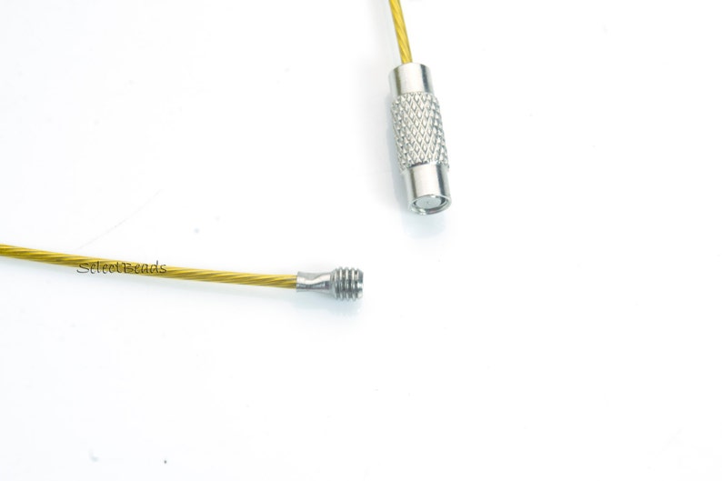May include: A gold-colored metal cable with silver-colored metal ends. The cable is flexible and has a slight twist. The ends are threaded and can be used to attach to other objects.