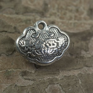 Könnte beinhalten: Silberner Anhänger mit einem Wolken-Design und chinesischen Schriftzeichen. Der Anhänger hat eine Öse oben zum Anbringen an einer Halskette oder einem Armband.
