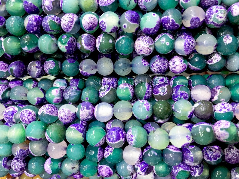 May include: A strand of green and purple agate beads. The beads are round and have a mottled appearance.