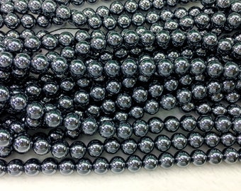 May include: A strand of shiny, black hematite beads. The beads are round and smooth, and they have a metallic sheen.