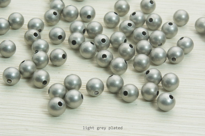 May include: A collection of light grey plated round beads with a matte finish. Each bead has a hole for stringing. The text "light grey plated" is visible at the bottom of the image. These beads are suitable for jewelry making.