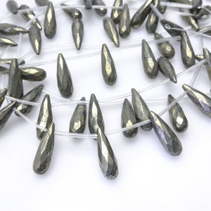 May include: A strand of metallic gray teardrop-shaped pyrite beads on a clear string. The beads are faceted and have a metallic sheen.