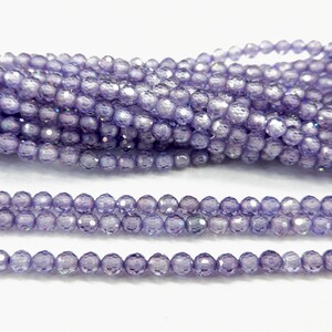 May include: A strand of iridescent purple glass beads. The beads are faceted and have a round shape.