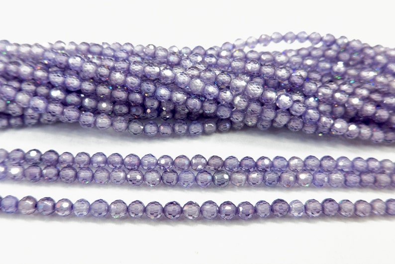 May include: A strand of iridescent purple glass beads. The beads are faceted and have a round shape.