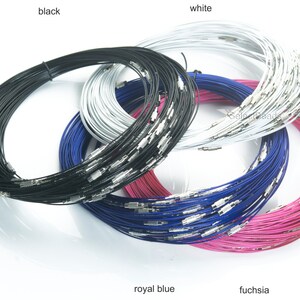 May include: A close-up of four spools of wire in different colors: black, white, royal blue, and fuchsia. The wire is thin and appears to be made of metal. The spools are stacked on top of each other.