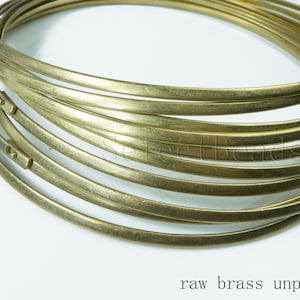 Puede incluir: Primer plano de una pila de anillos de alambre de lat&oacute;n en bruto, sin pulir y con un acabado natural ligeramente mate. Los anillos est&aacute;n apilados uno encima del otro, creando una forma circular.