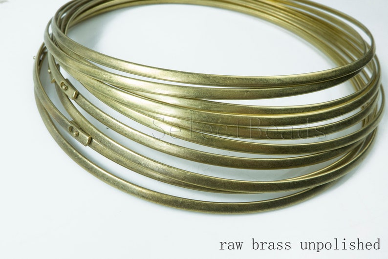 Puede incluir: Primer plano de una pila de anillos de alambre de lat&oacute;n en bruto, sin pulir y con un acabado natural ligeramente mate. Los anillos est&aacute;n apilados uno encima del otro, creando una forma circular.