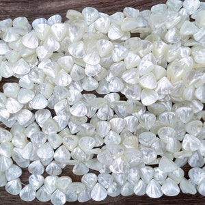 May include: A strand of white iridescent shell beads in a triangular shape. The beads are arranged in a random pattern and are all the same size.